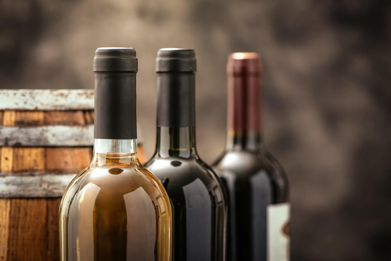 Wine bottles collection and wooden barrel in a wine cellar